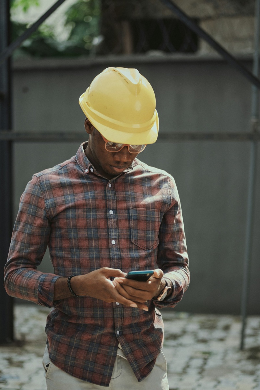 A tradie in a hard hat checking messages on his phone between jobs.